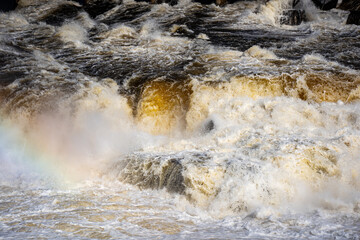 Fototapeta premium Close up of powerful river rapids with rainbow mist.