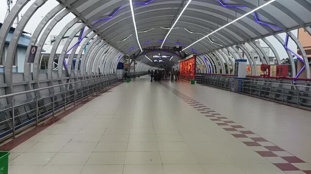 Saturday, 27 June 2026, in Howrah, West Bengal, India. Commuters walk inside a brightly lit modern arched metro station corridor.