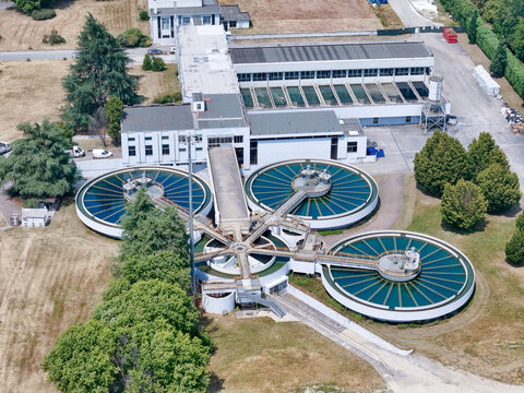 Aerial view of the water treatment plant on the Po River with large circular sedimentation tanks and industrial buildings in Torino, Piemonte, Italy.