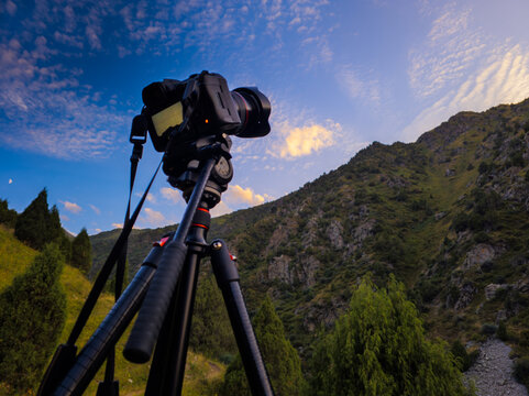 Camera on tripod photographing mountain landscape at sunset
