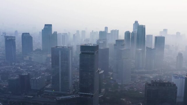 Stunning high-angle aerial view of a city skyscraper skyline enveloped in dense morning fog and smog.