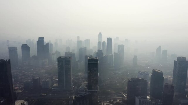 High-angle aerial view of modern city skyscrapers completely enveloped in dense white morning fog.