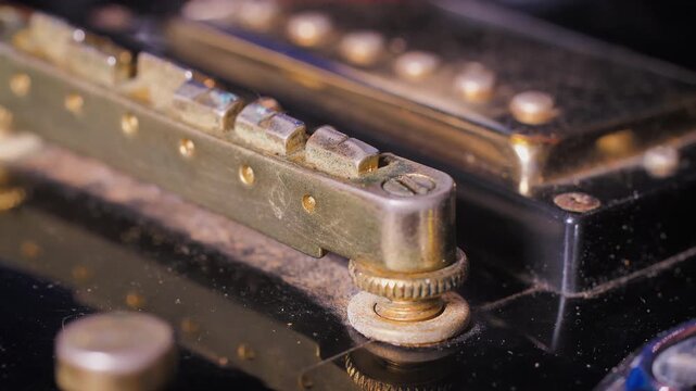 Close-up of a small brush cleaning an electric guitar, removing dust from the instrument during routine maintenance and care to keep hardware and surfaces clean