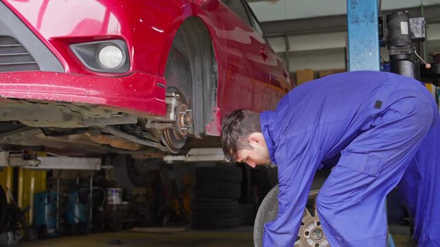 Man demonstrating how to change a tire in an auto repair shop with a detailed step by step guide for removing and replacing a car tire