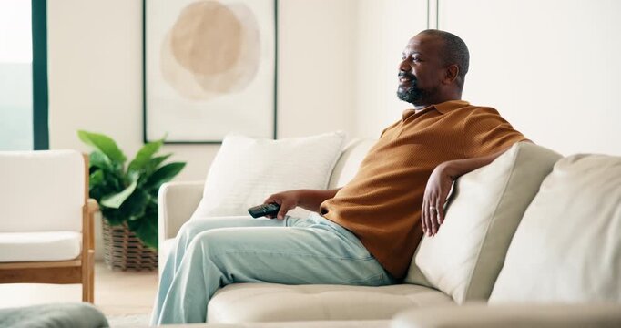 Man, laugh and watching tv in living room with remote, relax or joke for comedy show on weekend break. Mature, black person and change channel in home with tech, streaming funny film or entertainment