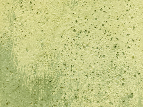 A close-up shot captures the rough, weathered texture of an old concrete wall. The surface is uneven, dark patches, mineral stains, and reflecting natural aging