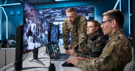 Fototapeta premium Military Intelligence Team Monitors Missions Using Laptops