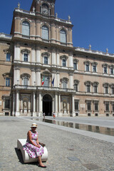 Obraz premium Senior women tourist sat on a bench in front of the Palazzo Ducali DI Modena, Emilia Romagna, Italy