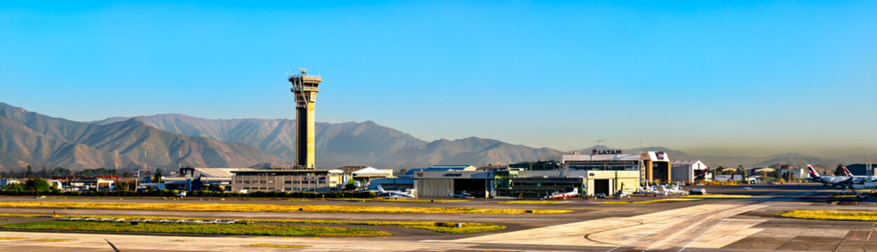 Pudahuel, Chile - October 13, 2025: Panorama of the air traffic control tower and maintenance hangars at Arturo Merino Benitez International Airport with the Andes mountains behind.