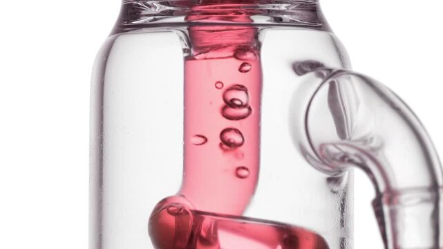 Reddish transparent liquid flowing through a glass tube, causing bubbles to condense and chaotically move inside it on a white backdrop | Roselle tea infusion cosmetic product ingredient concept