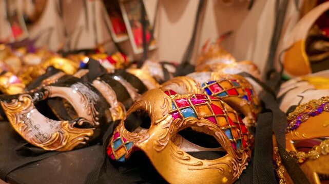 Close-up of beautiful traditional carnival masks on display in a souvenir shop. Slow camera push-in on an ornate gold and colorful harlequin masquerade mask