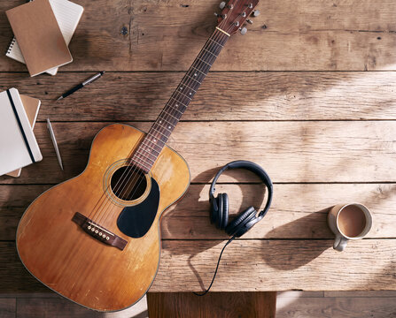 A top view of a guitar  coffee  and music equipment on a wooden table.