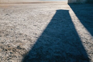 Obraz premium Long Shadow Cast by Large Wall on Flat Ground in Bright Outdoor Setting
