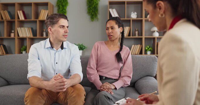 Couple counseling therapy with psychologist amid conflict. They sit on a sofa in an office, sharing talk and seeking consultation to rebuild trust. Relationship communication and support focus.