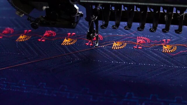 Multi head industrial embroidery machine sewing floral designs on blue fabric textile stitching