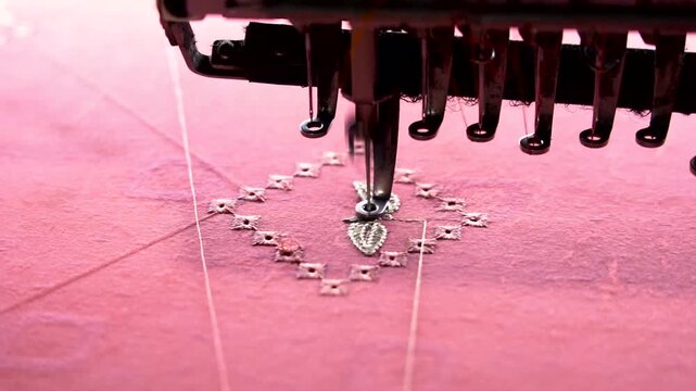 Industrial embroidery machine head sewing diamond pattern on pink fabric stitching textile