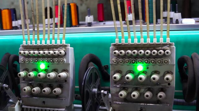 Industrial textile machine heads with colorful thread spools in clothing factory embroidery