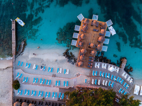 Aerial view of Ksamil beach with wooden decks, straw umbrellas, rows of sun loungers, and turquoise water in Ksamil, Vlore County, Albania.