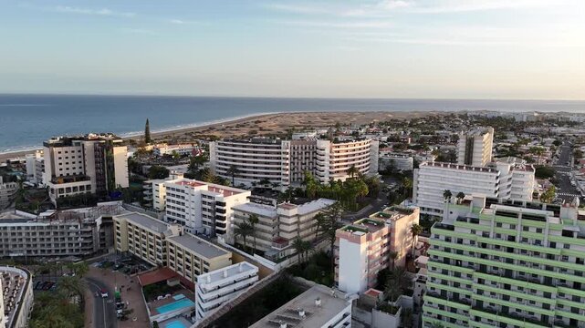 Aerial panorama flight over hotels in Playa del Ingles towards Maspalomas Dunes, beach and Atlantic ocean in the evening on Canary Island Gran Canaria, Spain