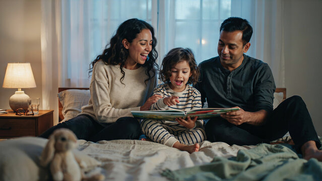 Multicultural family reading picture book together, authentic candid moment of parenting and connection
