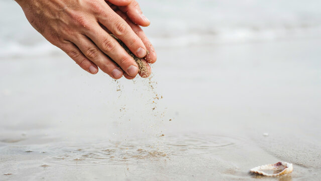 Fingers sifting through fine sand, tactile texture of beach sand grains