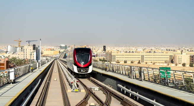 Riyadh, Saudi Arabia - February 21, 2026: A modern Riyadh Metro train travels along elevated tracks above King Abdullah Road with the city skyline and desert landscape in the background