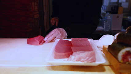 Japanese Chef Slicing Fresh Raw Tuna on White Cutting Board © blueringmedia