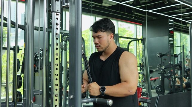 Muscular Man Performing Tricep Rope Pushdown at a Cable Machine
