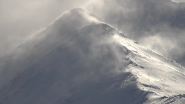 Caucasus, North Ossetia. The Bokovoy Ridge Mountains. A strong wind blows snow down the mountain slope.