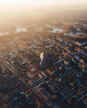 Aerial view of the historic star-shaped fortress of Vesting Naarden with its iconic moat, church, and dense urban rooftops bathed in golden hour light, Naarden, Noord-Holland, Netherlands.