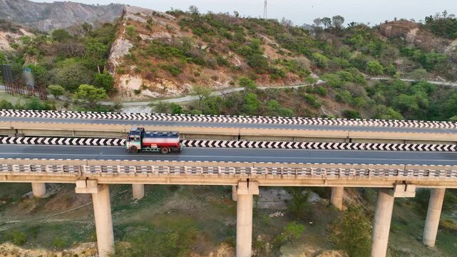 Aerial tracking of commercial cargo truck driving on elevated highway bridge.