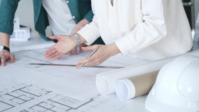 Architects discussing apartment building blueprint at office desk, using drafting tools for new architectural project design. Architecture and business concept