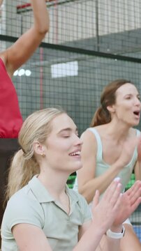 Vertical video: Reacting to point, blonde woman in green polo pumping fists, clapping behind net
