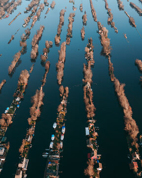 Aerial view of narrow land strips with small houses and boats moored along the calm water channels in Scheendijk, Breukelen, Utrecht, Netherlands.