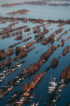 Aerial view of the unique narrow, tree-lined land strips of Scheendijk surrounded by calm water with small houses and moored boats in Scheendijk, Breukelen, Utrecht, Netherlands.