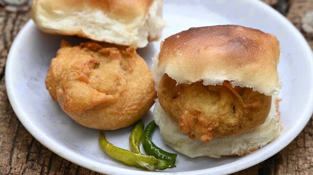vada pav, mumbai famous vada paav is an indian burger. potato patty is deep fried and stuffed inside a paav or bun like burger, served over a rustic wooden background