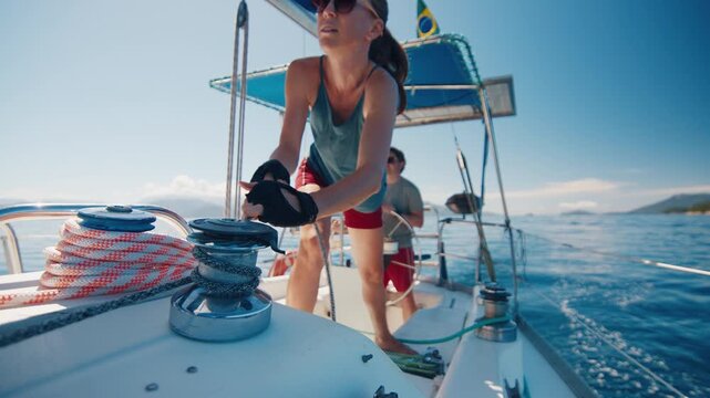 Sailing in the smooth sea during sunny day. Man and woman sail the small sailing boat in the region of the island of Ilha Grande in Brazil