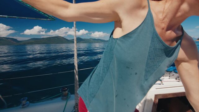 Sailing in the smooth sea during sunny day. Man and woman sail the small sailing boat in the region of the island of Ilha Grande in Brazil