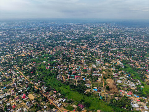 Aerial view of dense residential neighborhoods with colorful rooftops, lush green vegetation, and winding dirt roads stretching across the landscape in Monrovia, Liberia.