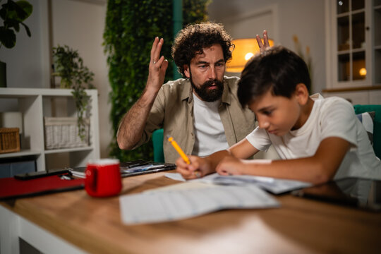 Frustrated father supervising son doing difficult homework