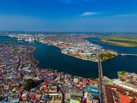 Aerial view of the dense urban landscape and coastal housing, featuring the bridge crossing the Mesurado River under a clear blue sky in Monrovia, Liberia.