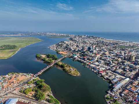 Aerial view of the Mesurado River flowing through the urban landscape of Monrovia with a bridge connecting city districts and the Atlantic Ocean coastline, Monrovia, Liberia.