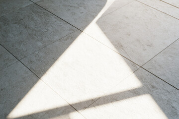 Fototapeta premium Sunlight clean tile floor bright beam minimalist surface copy space fresh sanitation empty space indoor light shadow line white tile gray tile clean floor beam of light geometric pattern abstract