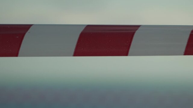 Barrier tape warning, red and white striped danger line moving against a blurry background, symbolizing caution and restriction