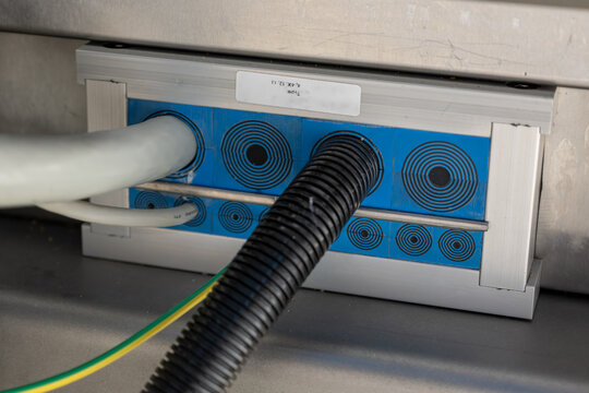 Close-up of a cable gland entry on an electrical distribution board with a cable.