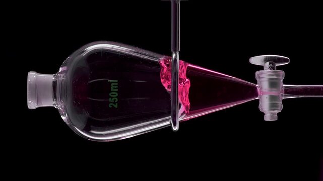 Detailed frame of soft pink transparent liquid is injected into a separatory funnel, producing splashes within the liquid standing against black | Cranberry liquid extract cosmetic substance concept