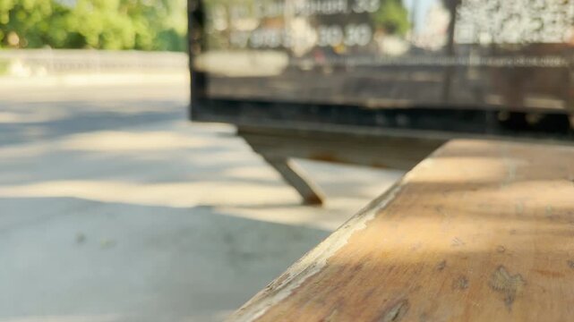 An empty wooden bench catches bright sunlight at a quiet bus stop in Simferopol, Crimea. This lonely scene evokes a peaceful and nostalgic feeling.