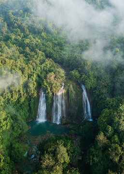 Aerial view of Cikaso Waterfall surrounded by lush tropical rainforest and mist, West Java, Indonesia.