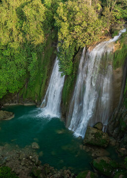 Aerial view of Cikaso Waterfall featuring cascading water flowing into a turquoise pool surrounded by lush tropical vegetation and rocky cliffs in West Java, Indonesia.