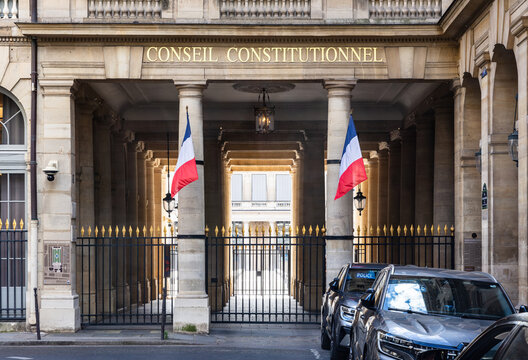 Paris, France - June 17, 2026: Portico decked with french flags in the Palais Royal, home of the Constitutional Council, the highest constitutional authority, with unmarked police cars parked in front
